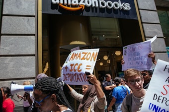 caption: Protesters march to an Amazon store to raise awareness of Amazon facilitating ICE surveillance efforts.