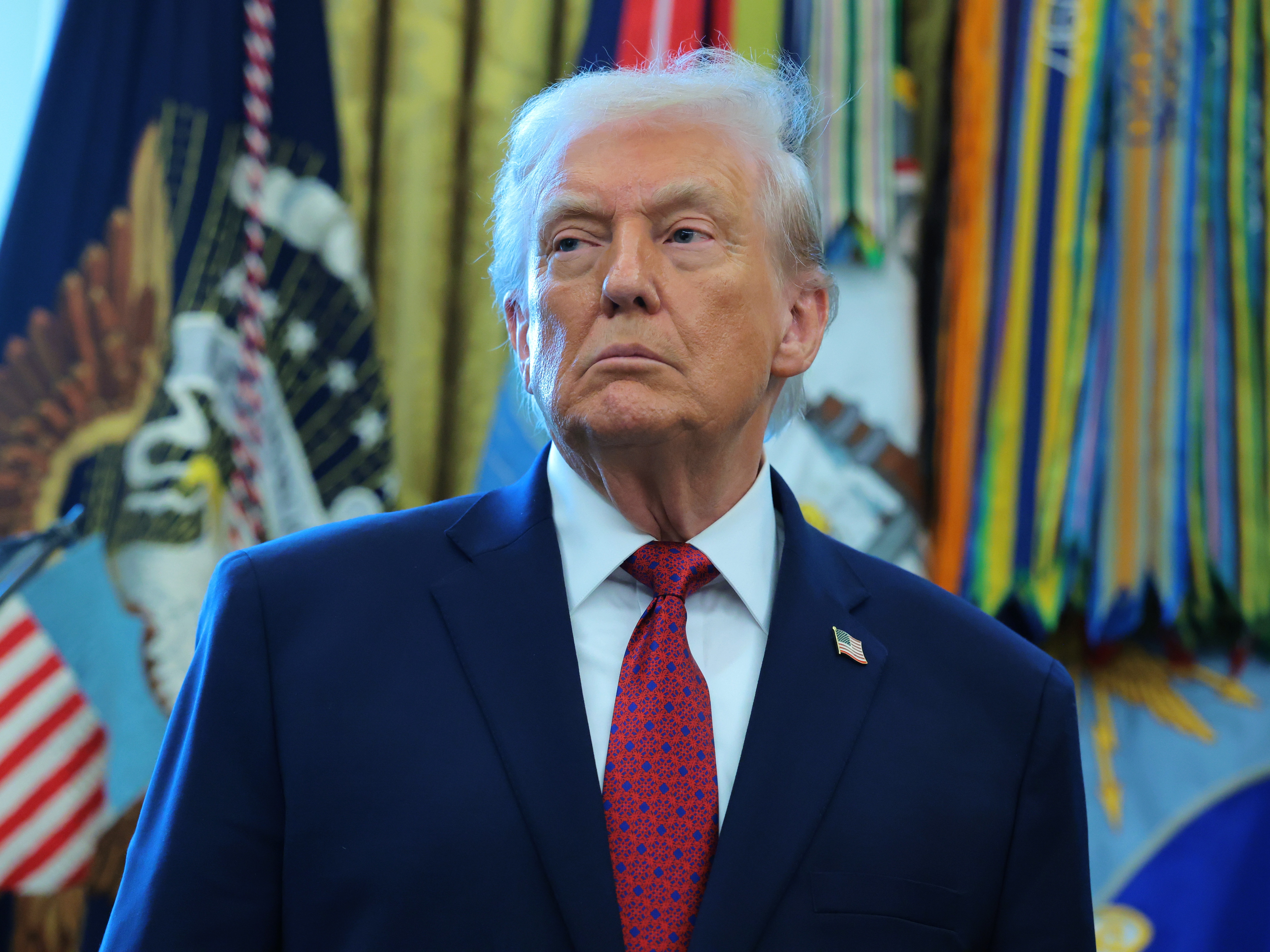 caption: President Trump listens during a ceremony for the presentation of the Mexican Border Defense Medal in the Oval Office of the White House on December 15, 2025 in Washington, DC.