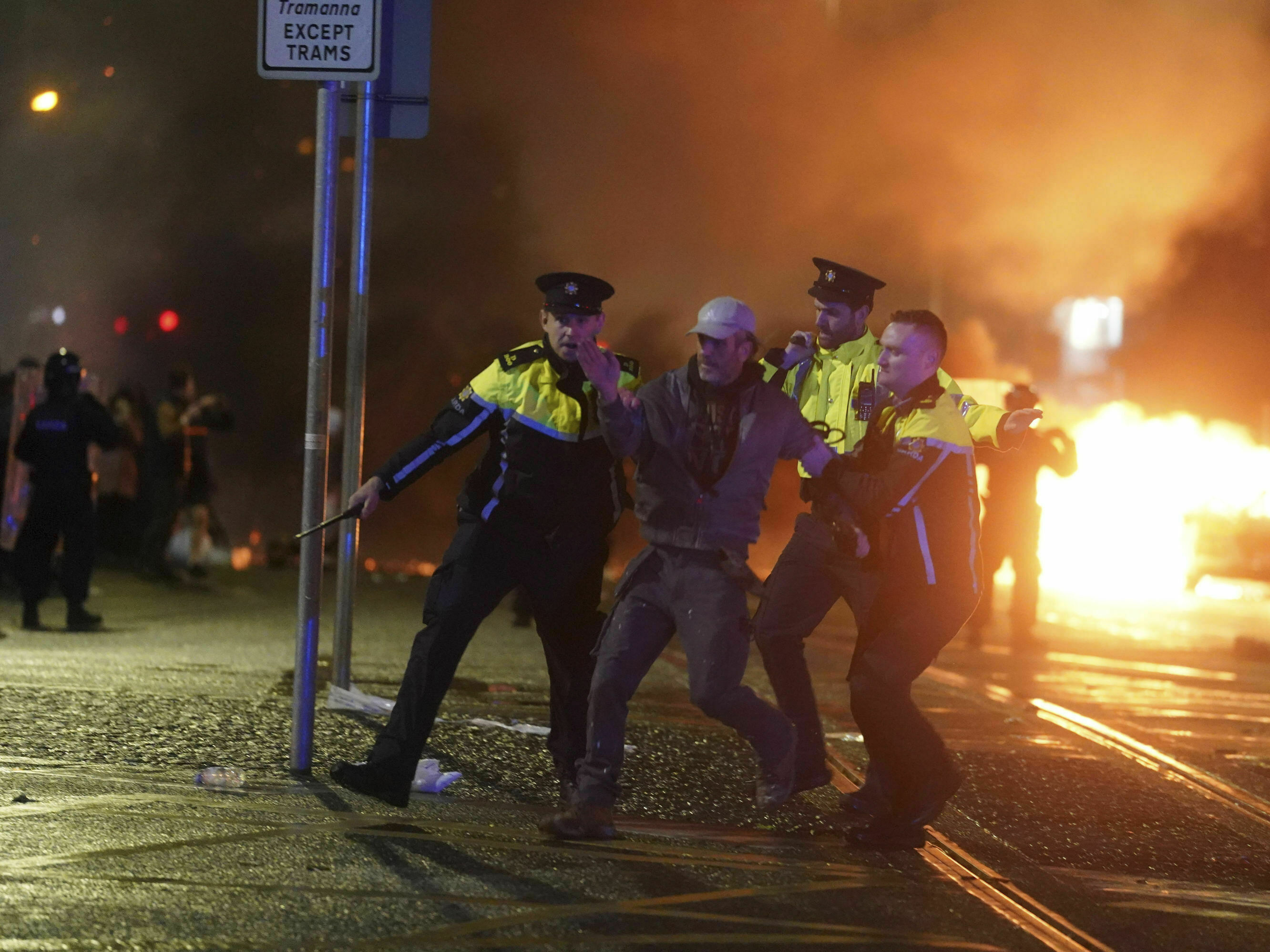 caption: Irish police officers apprehend a man after a demonstration near the scene of an attack in Dublin city center, on Thursday Nov. 23, 2023. The violence broke out following a knife attack that left a woman and two other children were injured.