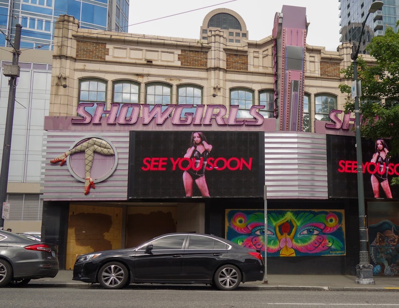 caption: The billboard at the Deja Vu Showgirls strip club in downtown Seattle invites customers to return when the lockdown ends. A few seconds later, the image is replaced by a message that reads, "Thank you doctors and nurses."