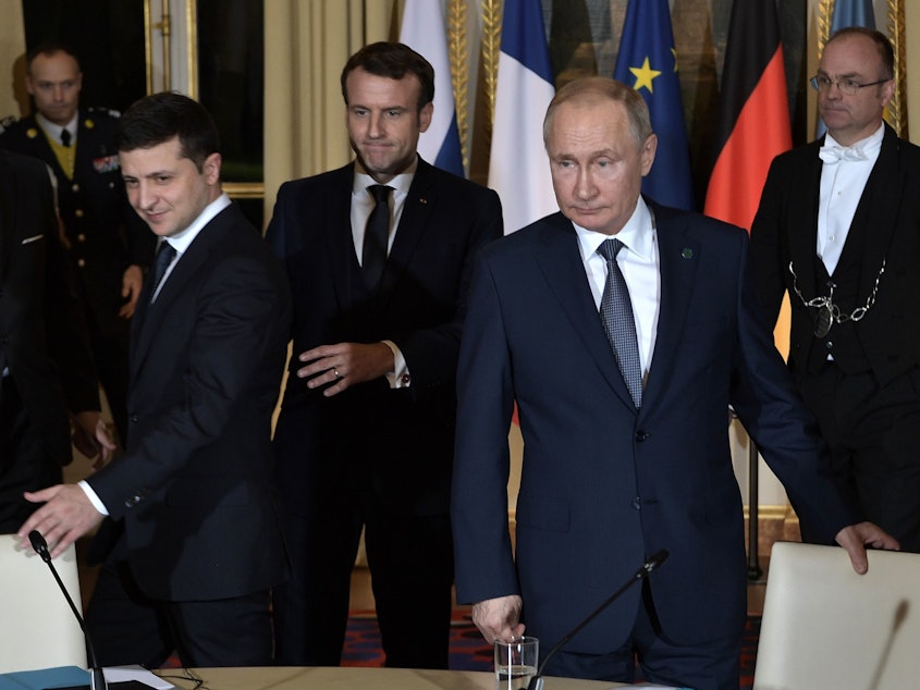 caption: Ukrainian President Volodymyr Zelenskiy, French President Emmanuel Macron and Russian President Vladimir Putin arrive for a meeting on Ukraine with German Chancellor at the Elysee Palace on Monday in Paris.