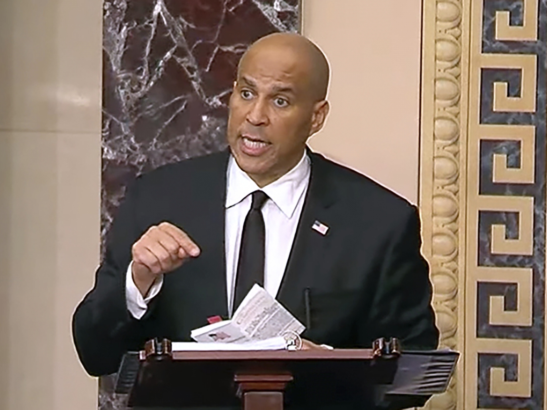 caption: Sen. Cory Booker speaks on the Senate floor on Tuesday morning. He took the podium at 7 p.m. Monday night and promised to stay there as long as physically possible.