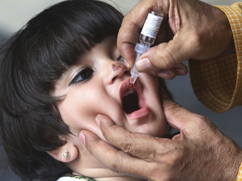 caption: A health worker gives the oral polio vaccine to a child in Karachi, Pakistan.