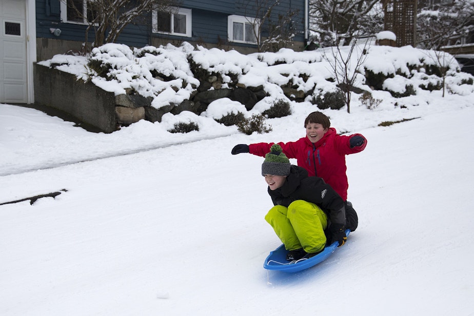 caption: Henry Smith, 9, and Lennox Benton, 9, right, sled down a closed street on Monday, February 11, 2019, near the intersection of 2nd and 70th Streets in Seattle.