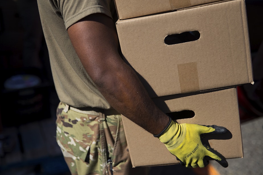 caption: Spc. Andre Bhatt with the Washington National Guard loads boxes of food into the back of a vehicle on Tuesday, September 22, 2020, at the Tukwila Pantry Food Bank on South 140th Street in Tukwila.