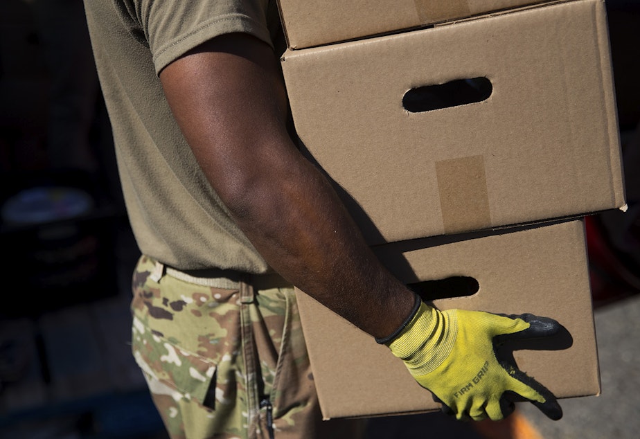 caption: Spc. Andre Bhatt with the Washington National Guard loads boxes of food into the back of a vehicle on Tuesday, September 22, 2020, at the Tukwila Pantry Food Bank on South 140th Street in Tukwila.