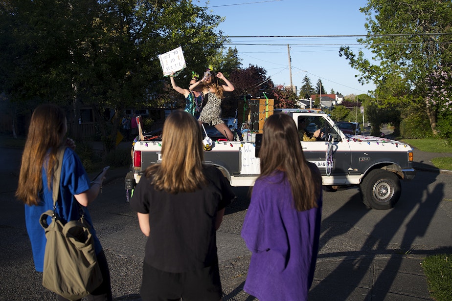 caption: The Seattle Quarantine Parade, including members Lindsey Hornickel, left, and Darcy Newby, right, drives through the Wallingford neighborhood on Friday, May 8, 2020, in Seattle.
