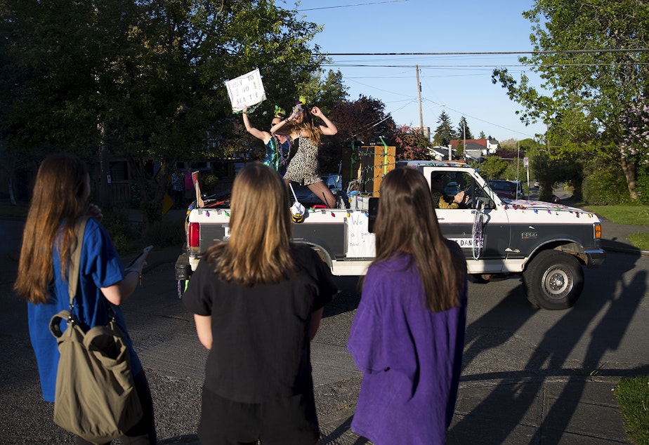 caption: The Seattle Quarantine Parade, including members Lindsey Hornickel, left, and Darcy Newby, right, drives through the Wallingford neighborhood on Friday, May 8, 2020, in Seattle.