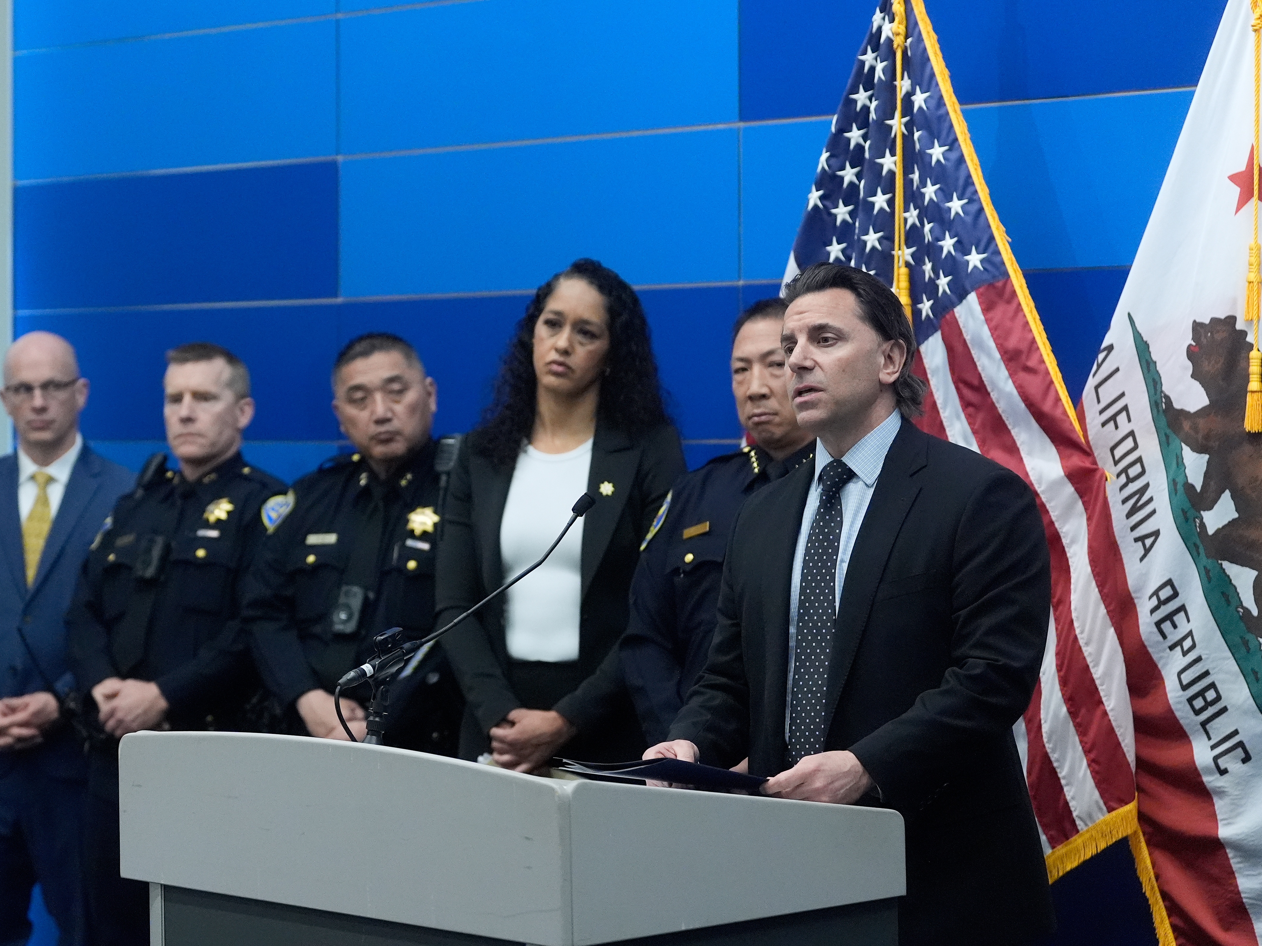 caption: Matt Cobo, F.B.I. San Francisco Acting Special Agent in Charge ( right) speaks next to San Francisco Police Chief Derrick Lew (second from right) and San Francisco District Attorney Brooke Jenkins (third from right) during a news conference Monday, April 13, 2026, in San Francisco.