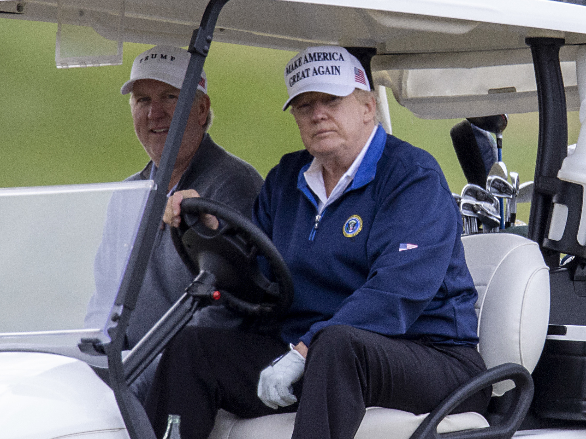 caption: President Trump drives a golf cart Sunday at Trump National Golf Club in Sterling, Va.
