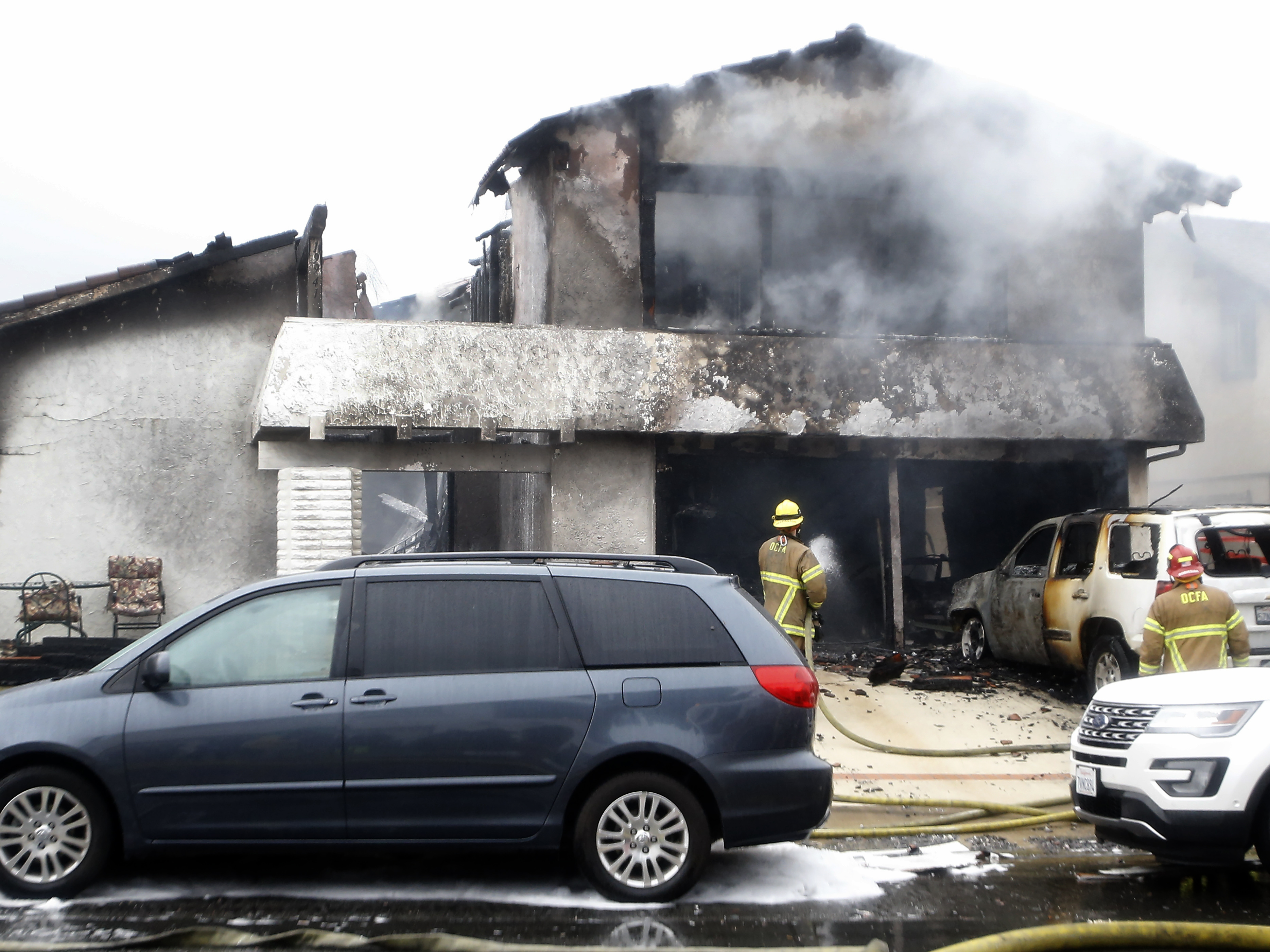 caption: Firefighters work in the driveway of a house where a deadly plane crash occurred in Yorba Linda, Calif., Sunday. Officials say five people died in the incident, including the pilot and four people who were in the house.