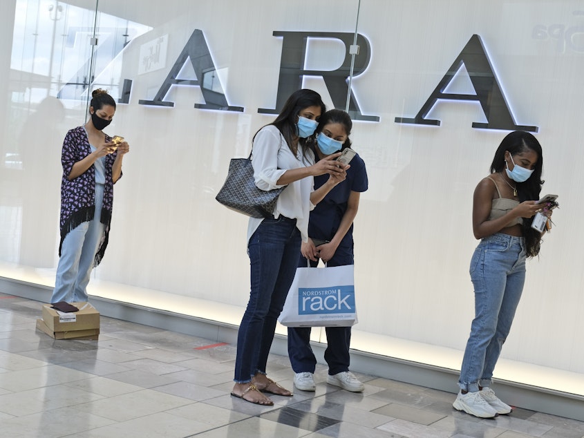 caption: Customers wait in line to enter a Zara store inside the newly reopened Garden State Plaza mall in Paramus, N.J., on June 29.
