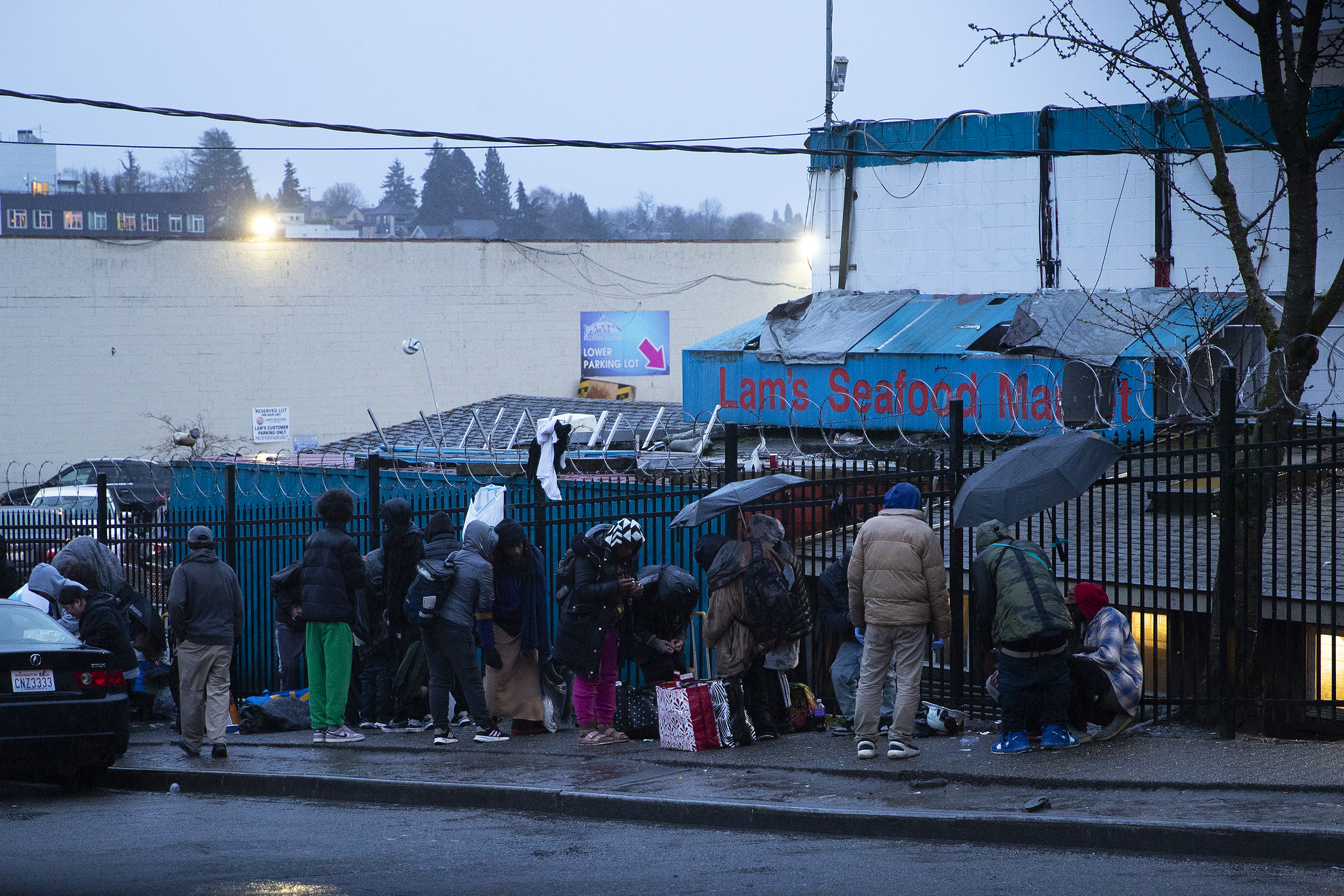 caption: A crowd of people is gathered on the sidewalk outside of Lam’s Seafood Market across from Hao Mai Park on Thursday, March 20, 2025, in Seattle’s Little Saigon neighborhood. 