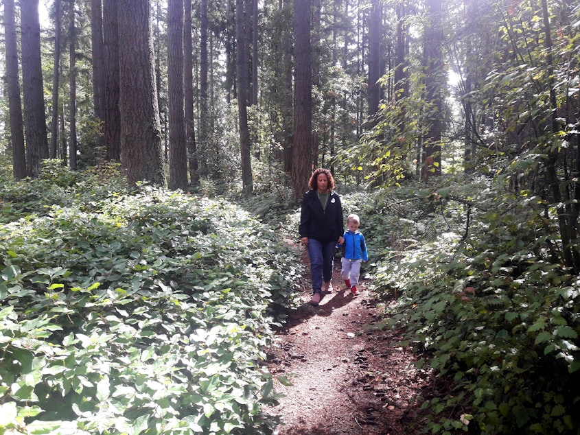 caption: Lori Sechrist of Save the Weyerhaeuser Campus walks a trail on the old campus with her grandson