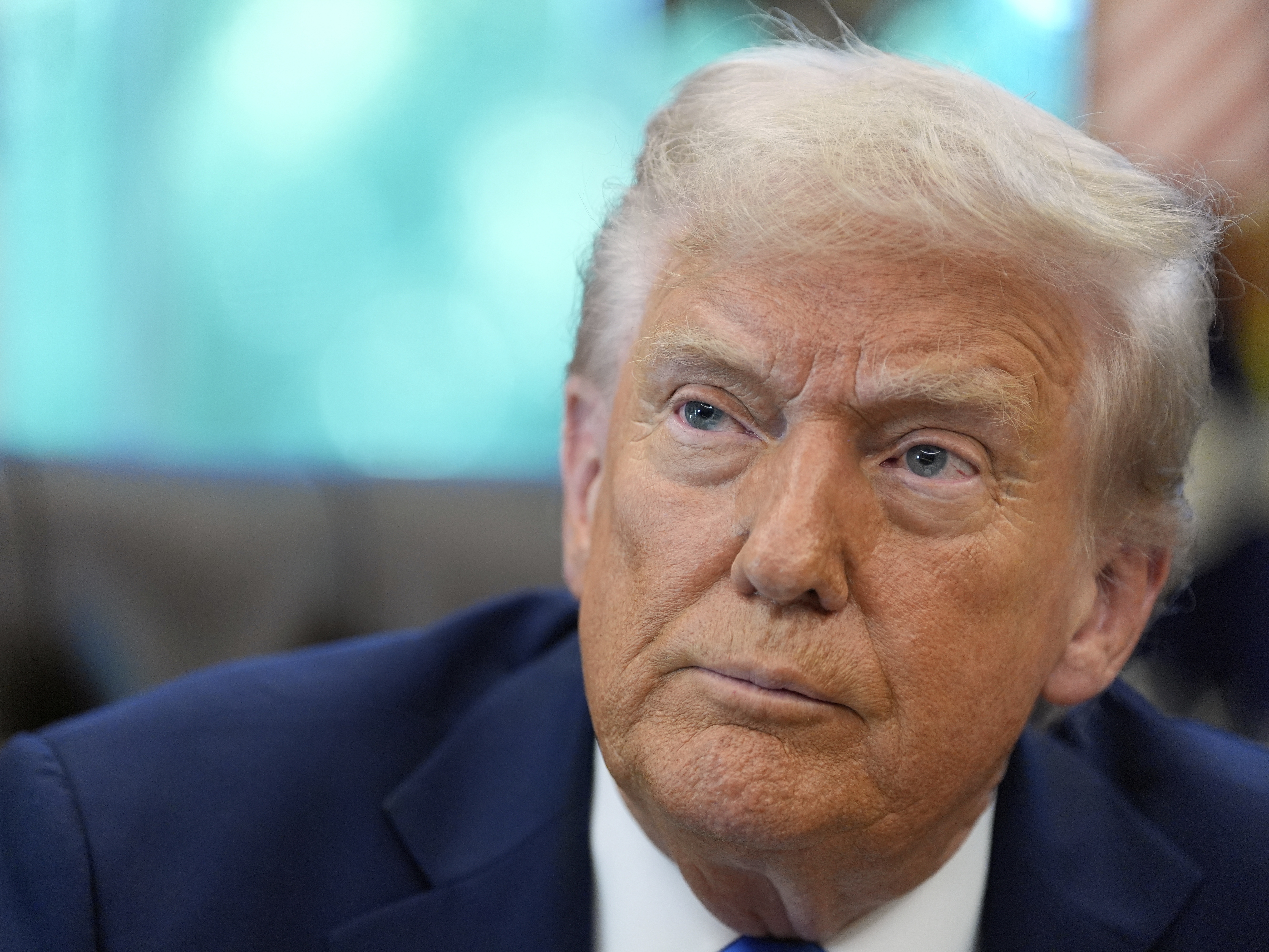 caption: President Trump listens to a reporter's question in the Oval Office of the White House on Friday.