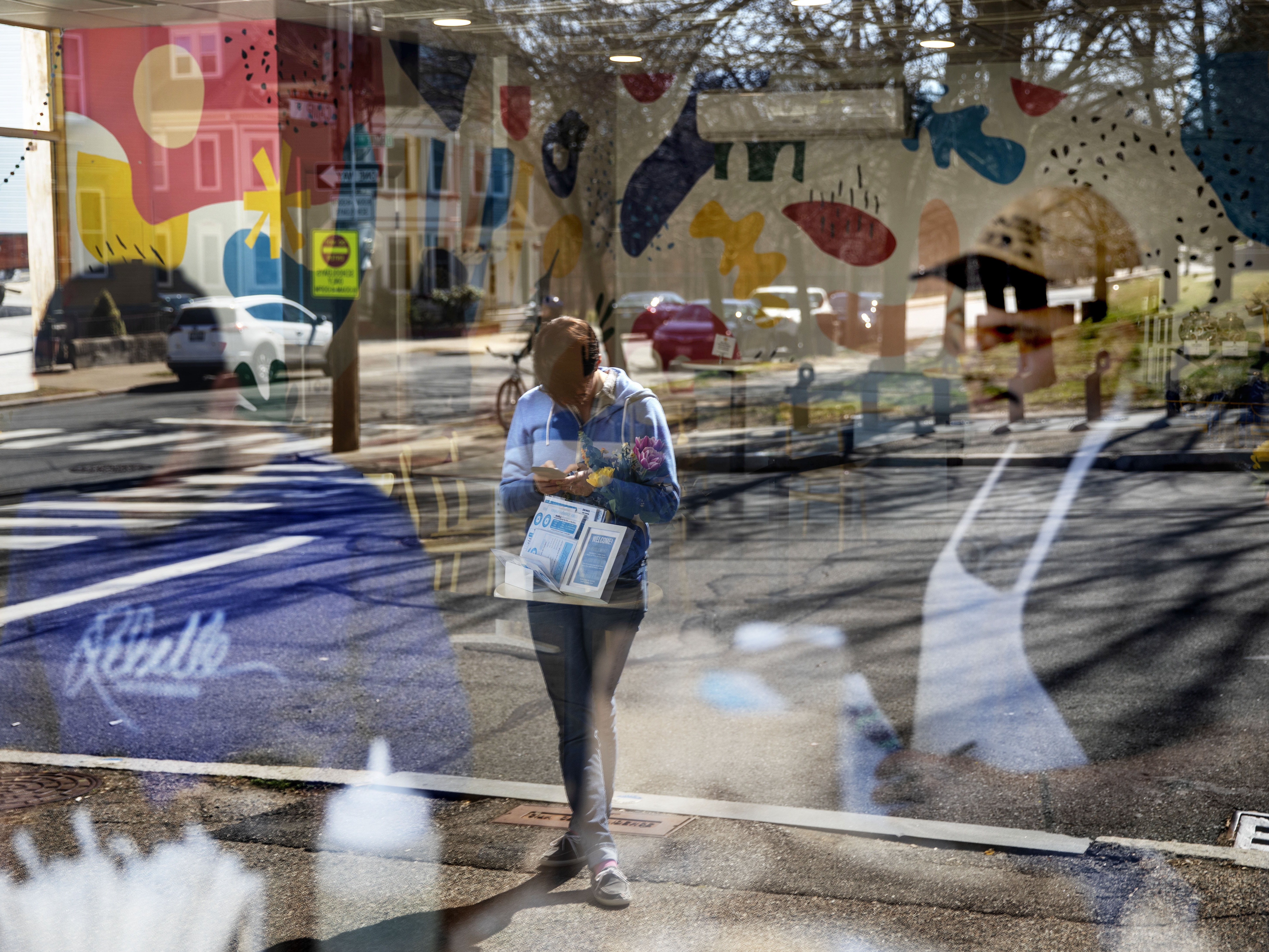caption: A customer waits for a take-out order as workers inside Rebelle Artisan Bagels in Providence, R.I., fill online orders to hand to waiting customers outside.