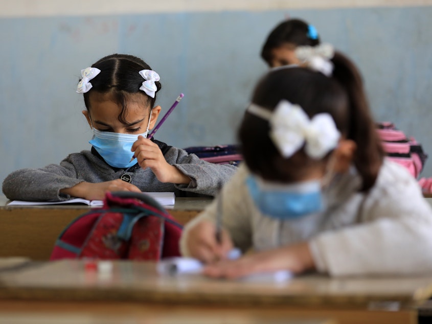 caption: Students wear masks at a school in Baghdad.