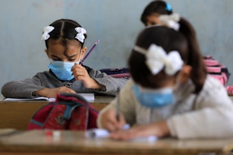 caption: Students wear masks at a school in Baghdad.