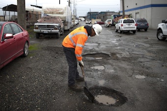 caption: Seattle Department of Transportation employee Koli Makasini gets ready to fill a pothole on Tuesday, January 8, 2019, at the intersection of South Forest Street and Occidental Avenue South in Seattle. 