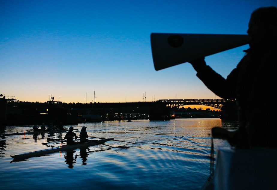 caption: Coach Rachel Kehler, right, shouts to members of the Pocock Rowing Club women's competitive team during an early morning training session, September 16, 2021. The team is training for the upcoming Head of the Charles Regatta in Boston at the end of October.