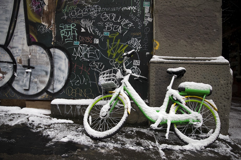 caption: A lime bike covered in snow rests against a building on Monday, February 4, 2019, in Pioneer Square at the intersection of 2nd Avenue and Yesler Way in Seattle. 