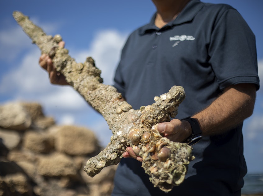 caption: Jacob Sharvit, director of the Marine Archaeology Unit of the Israel Antiquities Authority, holds a sword that experts say dates back to the Crusaders in Cesarea, Israel, on Tuesday.