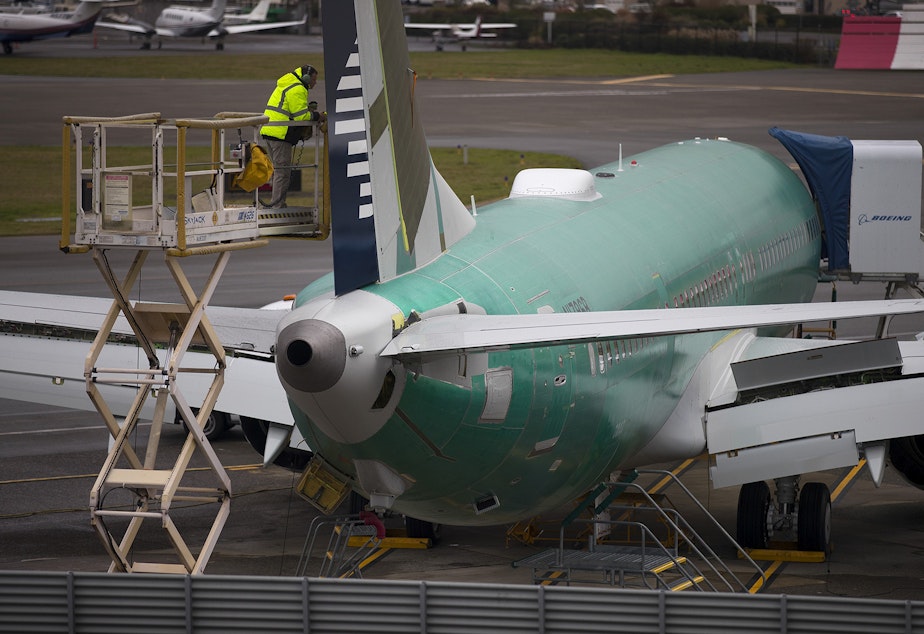 caption: A Boeing employee works on a 737 MAX on Monday, December 16, 2019, in Renton.