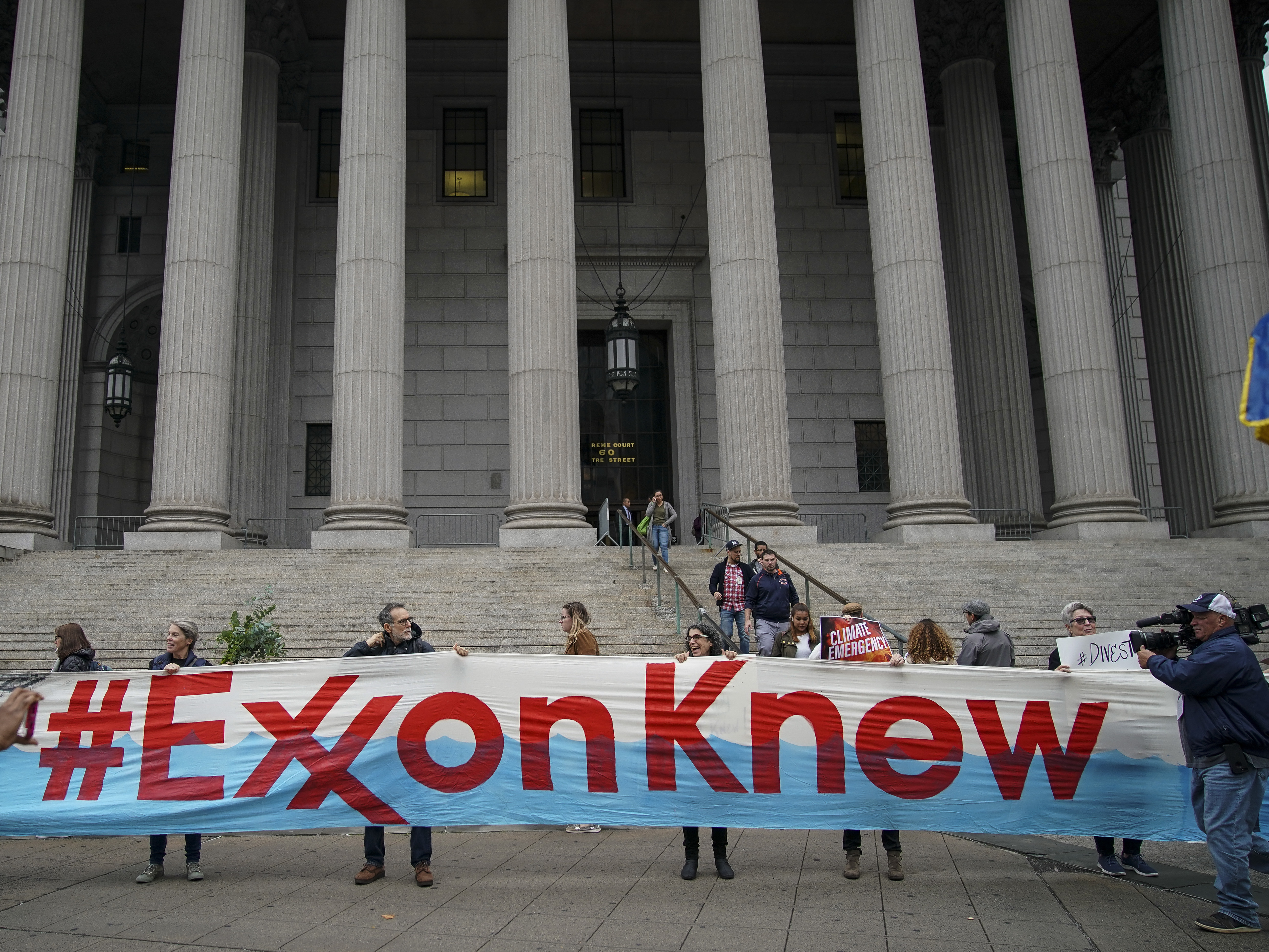 caption: Environmental activists rally outside of New York Supreme Court in October in Manhattan, the first day of the trial accusing ExxonMobil of misleading shareholders about its climate change accounting.