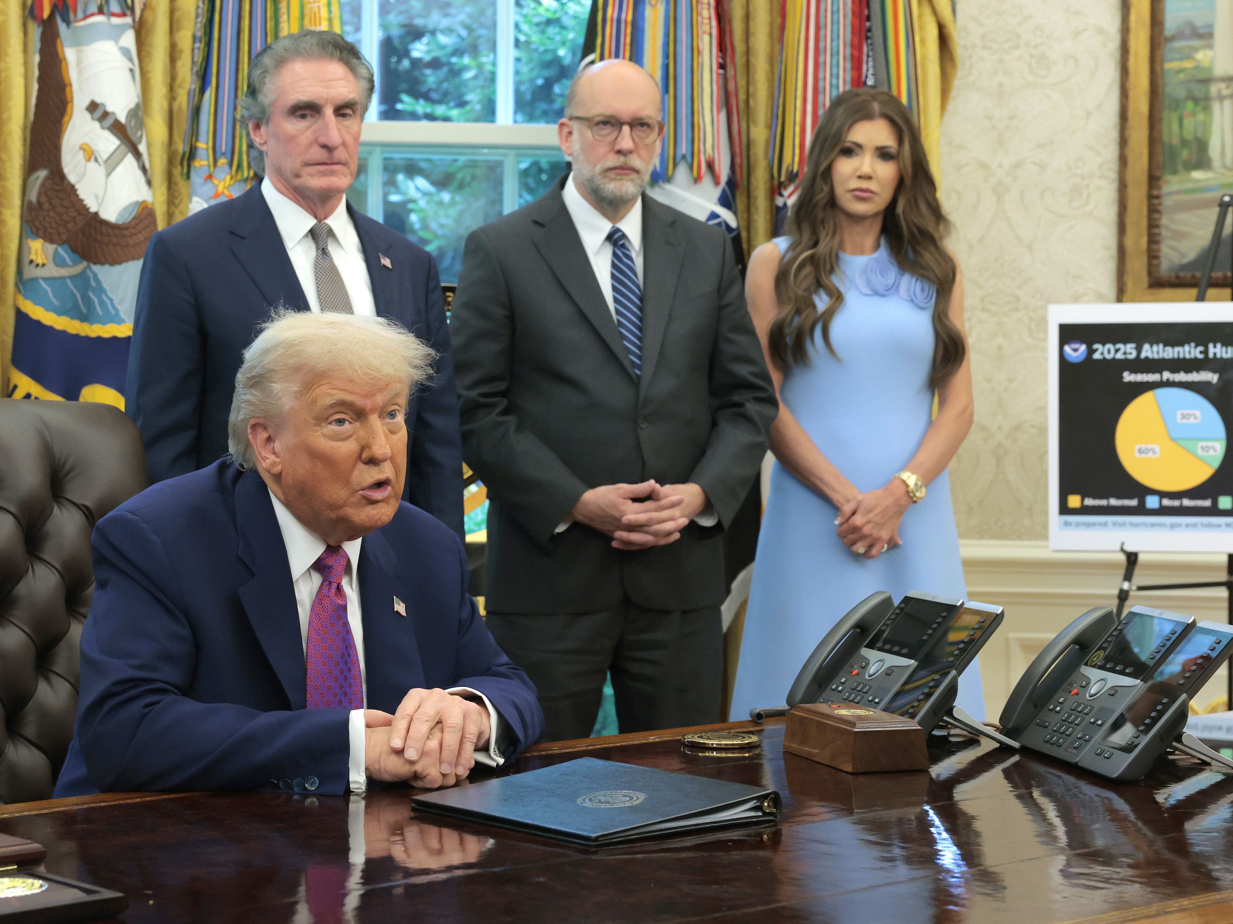 caption: OMB Director Russell Vought (center, behind President Trump) is the lead plaintiff in a lawsuit brought by four state attorneys general over more than $600 million in cuts to CDC grants announced this week. Homeland Security Sec. Kristi Noem and Interior Sec. Doug Burgum are also pictured in the Oval Office in June 2025.