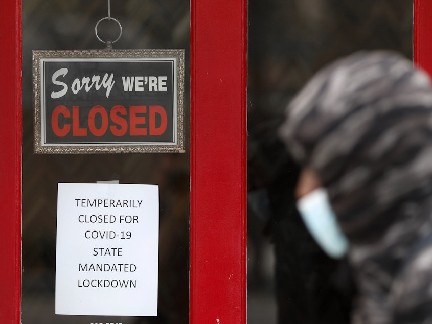 caption: A pedestrian walks by a closed shop in Grosse Pointe, Mich., on Thursday. The Labor Department is expected to report on Friday that the U.S. lost millions of jobs last month because of the coronavirus pandemic.