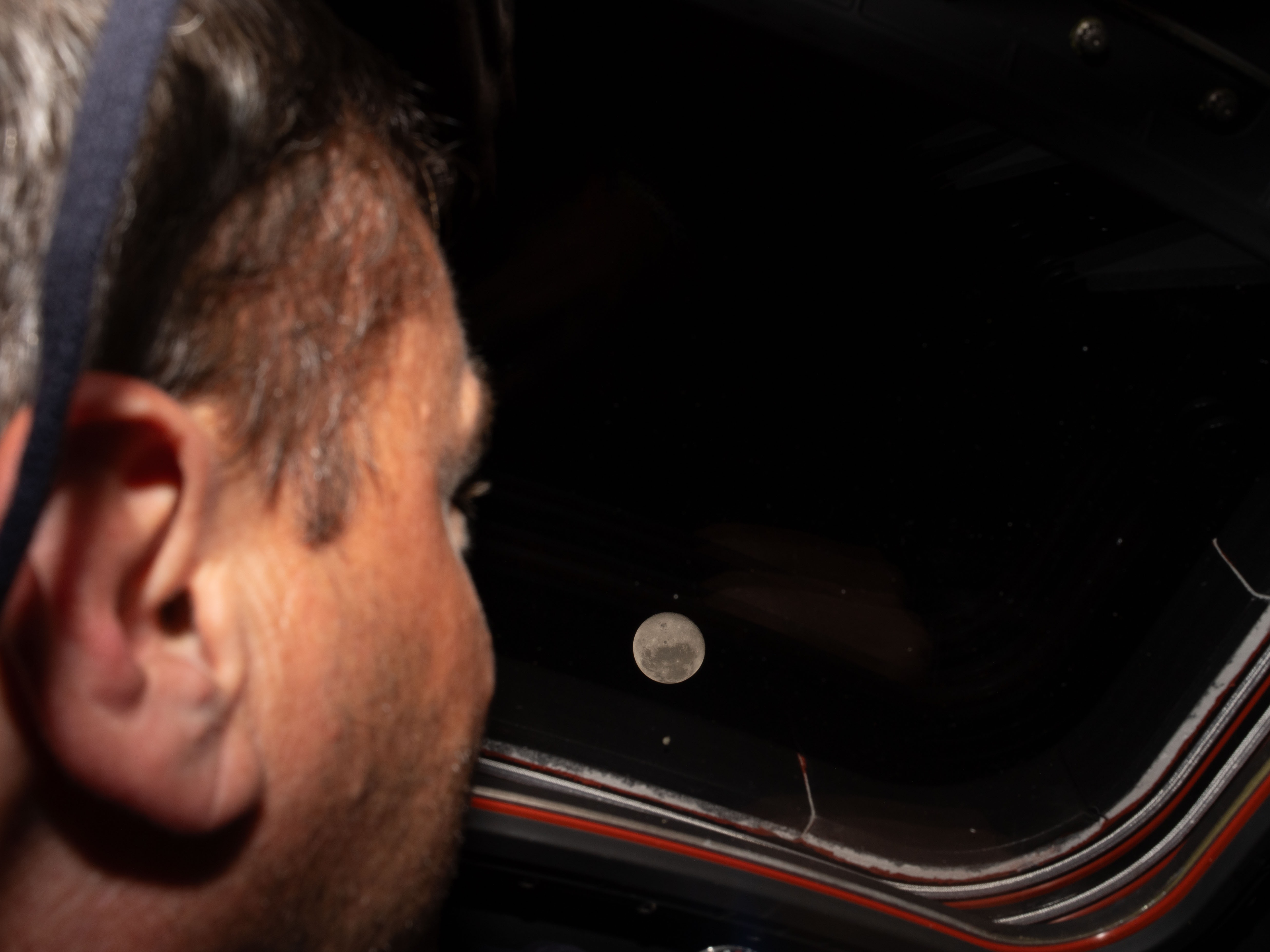 caption: Artemis II commander Reid Wiseman looks out one of the Orion spacecraft's main cabin windows at the Moon ahead of the crew's historic lunar flyby on Monday.