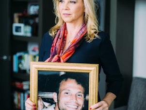 caption:  Cammie Wolf Rice holding a photo of her son Christopher