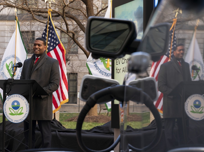 caption: Environmental Protection Agency Administrator Michael Regan is reflected in an electronic vehicle as it charges as he speaks during an event to announce a final rule for federal greenhouse gas emissions standards for cars and trucks on Monday.