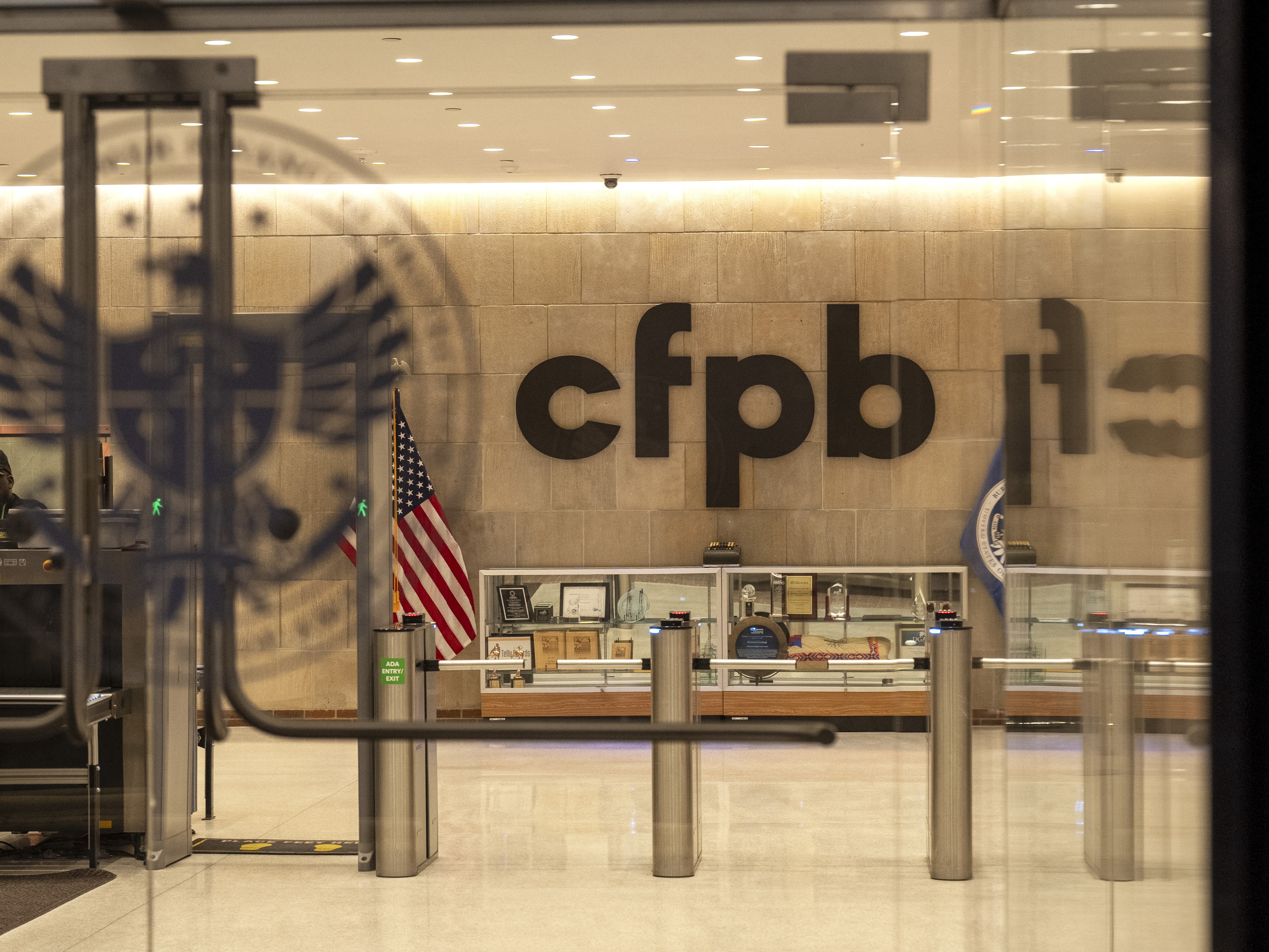 caption: A security officer works inside of the Consumer Financial Protection Bureau (CFPB) building headquarters on Monday in Washington. Staff and contractors have been told the building is closed for the week, and to perform no work.