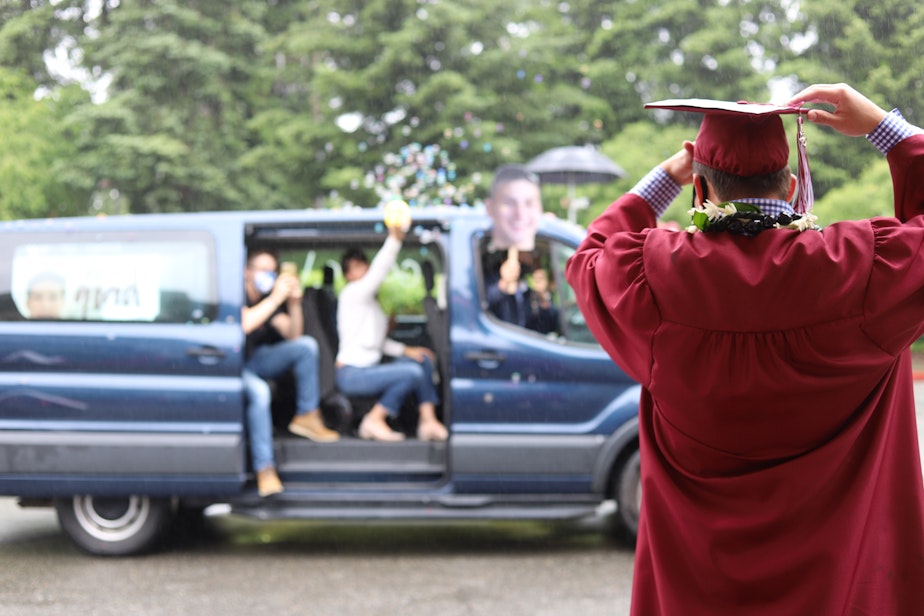 caption: Graduating senior Danny Scalzo adjusts his cap as his family cheers him on from a van on June 9, 2020. Along with an abnormal graduation, Scalzo, a varsity lacrosse player, dealt with a spring season cut short. For many seniors, the feeling of loss was particularly pronounced in their extracurricular experiences, where students have developed meaningful relationships and practiced their passions.