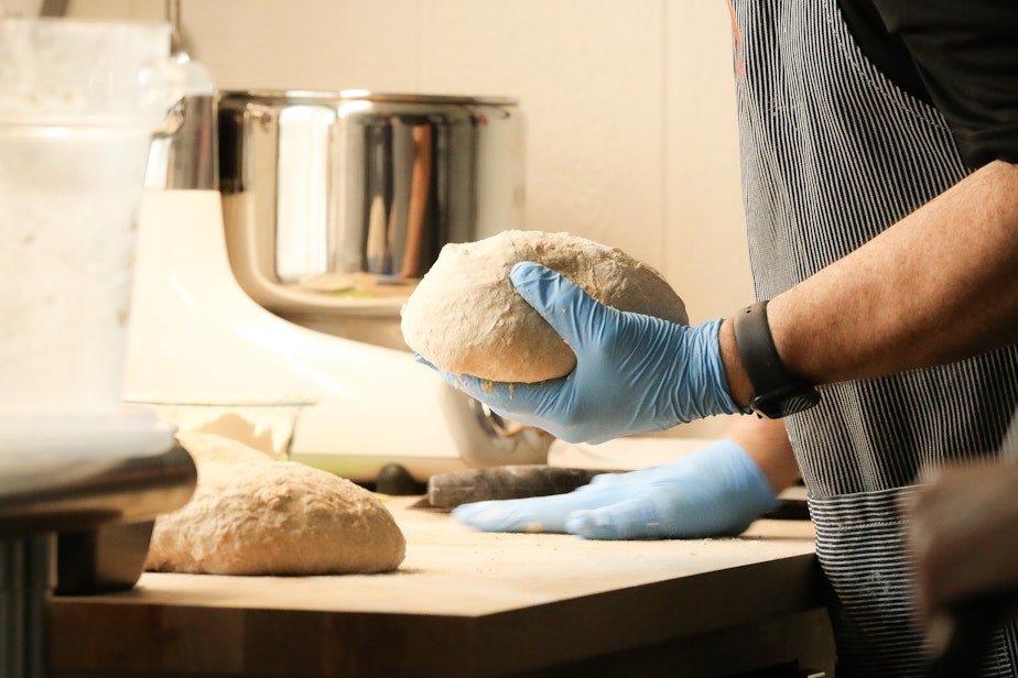 caption: Randy Cummings divides the bread dough into four parts that will be shaped into loaves. 