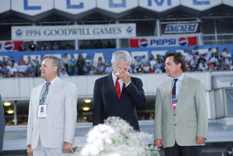 caption: Goodwill Games creator Ted Turner, center, wipes a tear from his eye after getting emotional during the lowering of the Goodwill Games flag during closing ceremonies in St. Petersburg, Russia, on Sunday, August 7, 1994. St. Petersburg Mayor Anatoly Sobchak is at left, Deputy Mayor Vitalby Myutko is at right. 