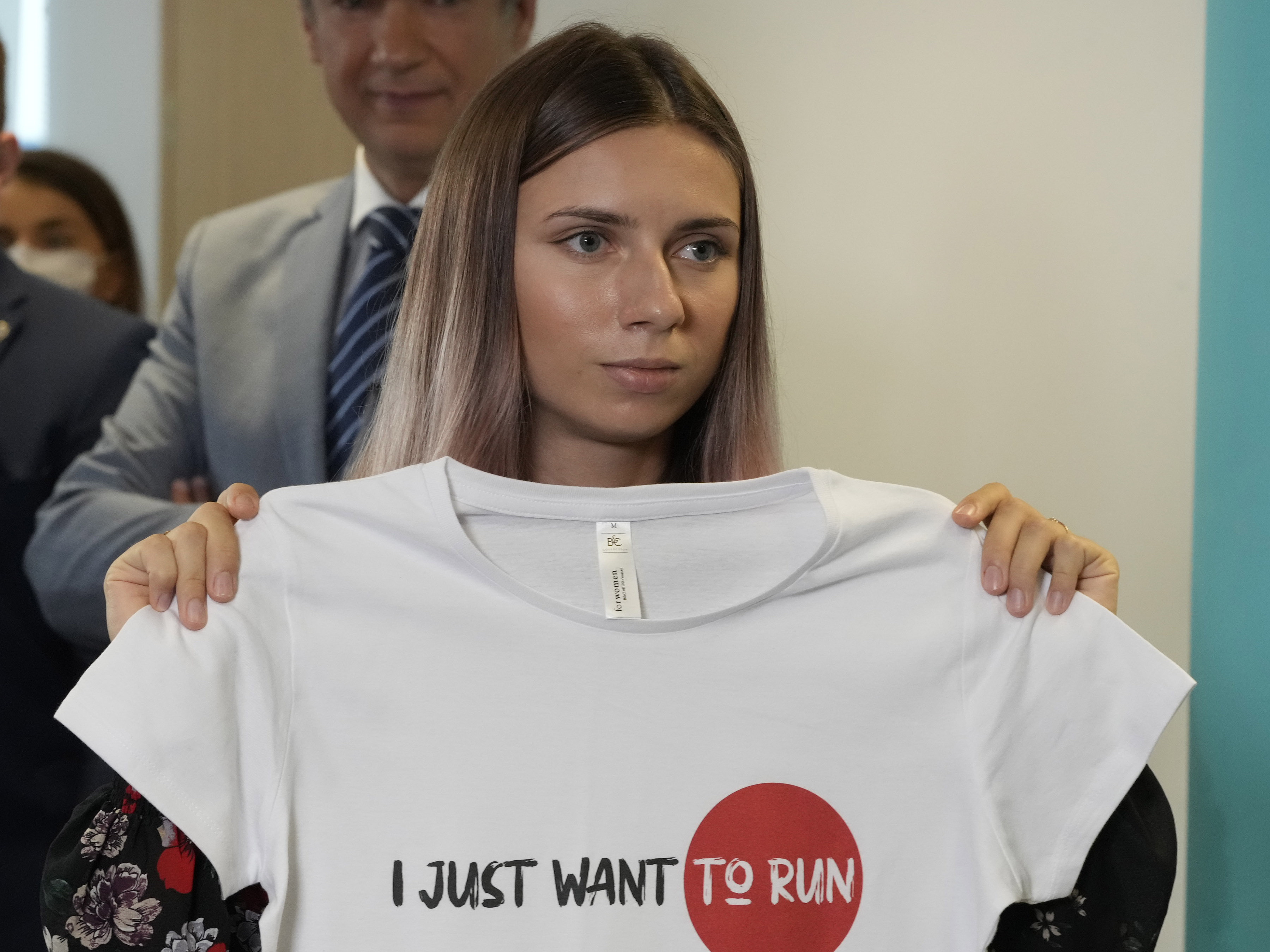 caption: Belarusian Olympic sprinter Kristina Timanovskaya, who arrived in Poland on Wednesday fearing reprisals at home after criticizing her coaches at the Tokyo Games, holds up an Olympic-related T-shirt with the slogan "I Just Want to Run" after her news conference in Warsaw, Poland, on Thursday.
