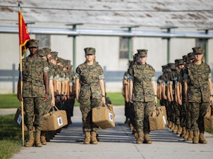 caption: Marine recruits wait for their drill instructor as they cross the base at Marine Corps Recruit Depot, Parris Island on August 22 in Beaufort County, S.C.