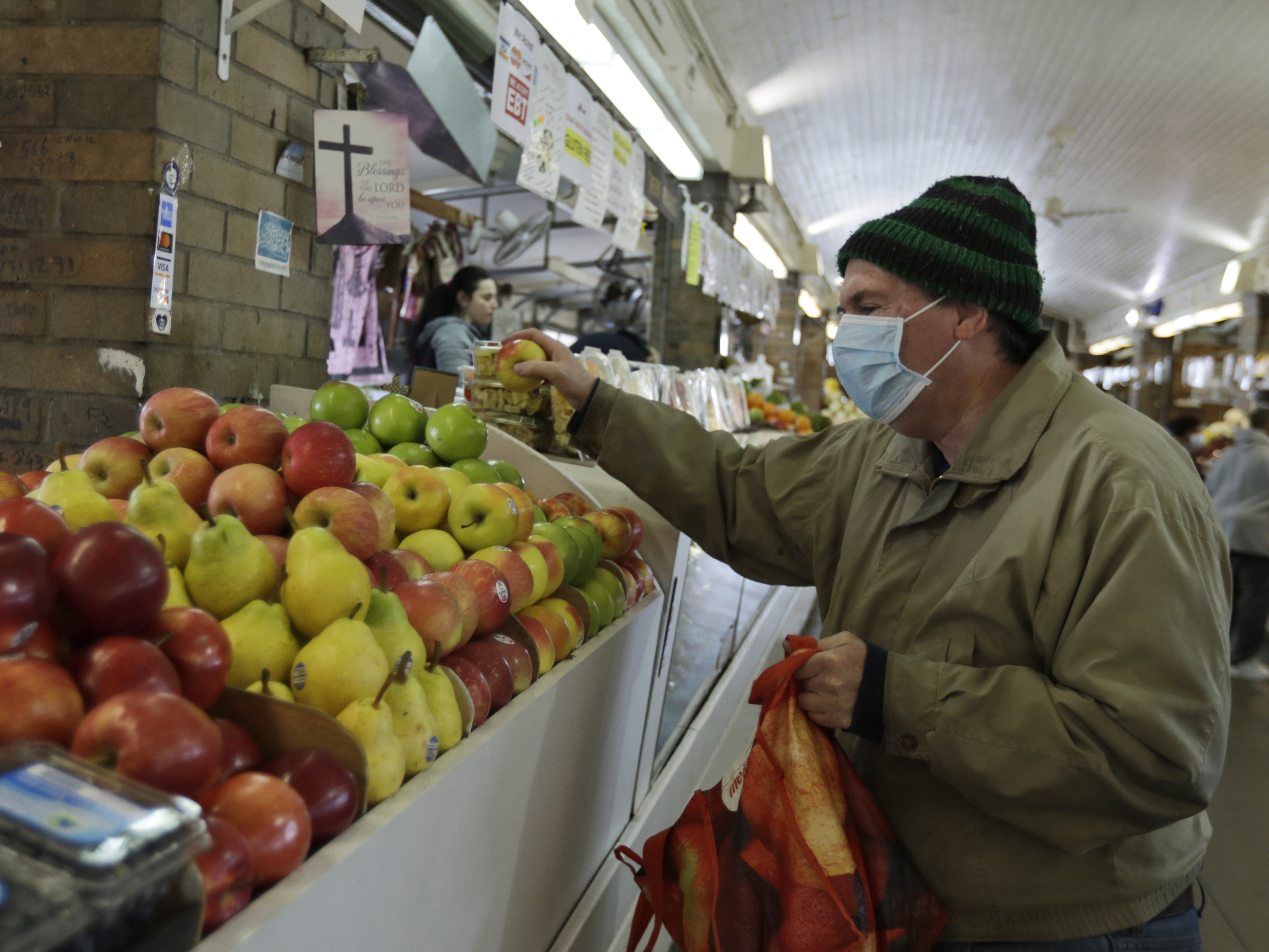 caption: Rick Wittenmyer shops for groceries at the West Side Market, Friday, April 10, 2020, in Cleveland. There were fewer shoppers this year before the Easter holiday than in previous years due to the coronavirus.