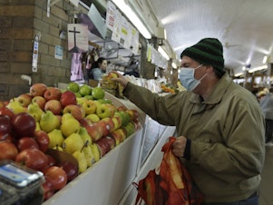 caption: Rick Wittenmyer shops for groceries at the West Side Market, Friday, April 10, 2020, in Cleveland. There were fewer shoppers this year before the Easter holiday than in previous years due to the coronavirus.