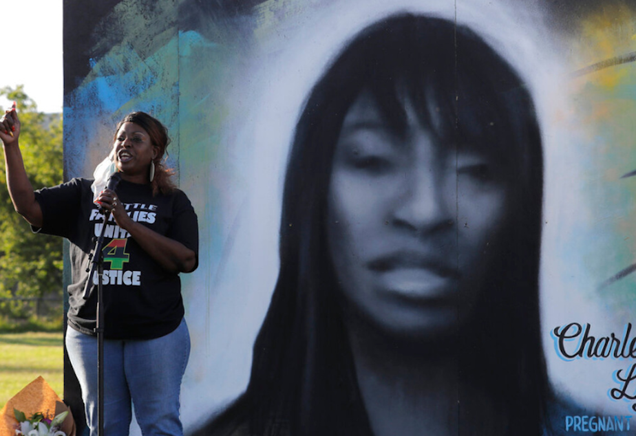 caption: Tonya Isabell, left, speaks Thursday, June 18, 2020, during a vigil for her cousin Charleena Lyles, pictured at right, on the third anniversary of her death, in Seattle. Lyles was shot and killed by Seattle police. Also in attendance at the vigil were family members of nearly two dozen people killed by police across the country who traveled to Seattle to urge police reform, an issue renewed by protests against the police killing of George Floyd in Minneapolis.