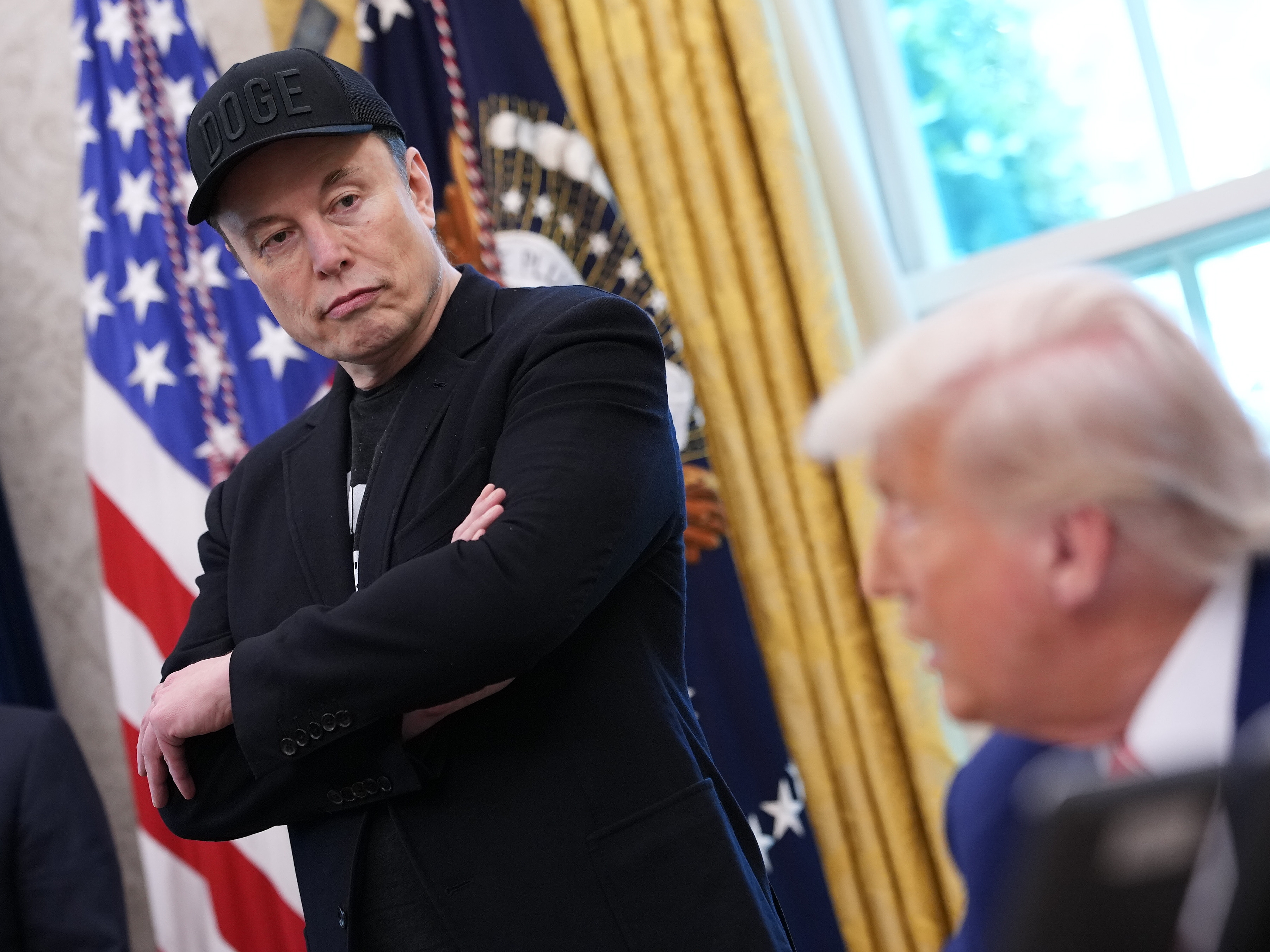 caption: Elon Musk listens as President Trump speaks to reporters in the Oval Office on May 30. A week after the two traded social media disses and threats, Musk said Wednesday some of his posts "went too far."