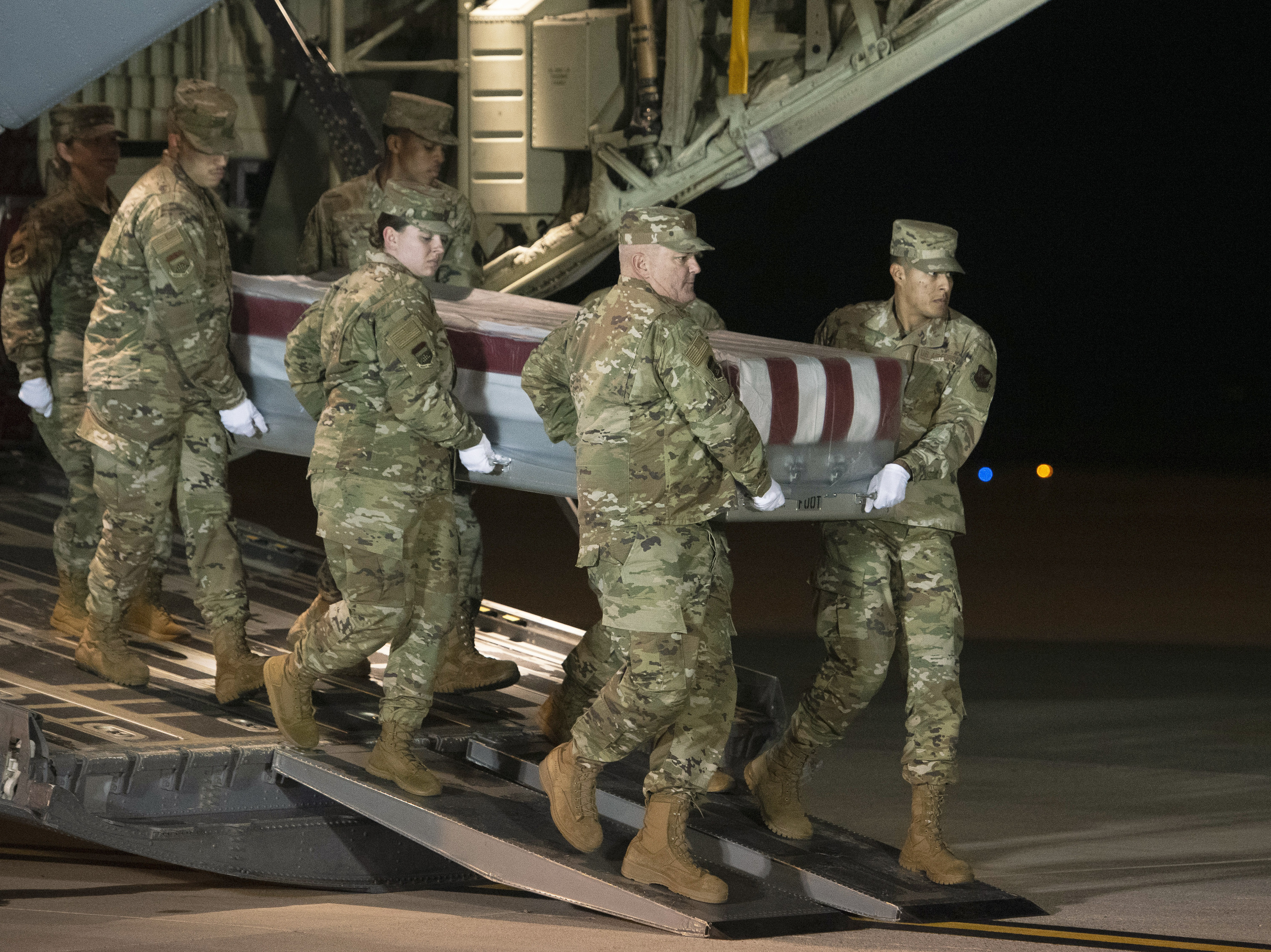 caption: An Air Force team moves a transfer case containing the remains of one of the young sailors killed after a Saudi military student opened fire at Naval Air Station Pensacola last month. Officials are expected to soon announce that about 20 Saudi military students will be expelled from the U.S.