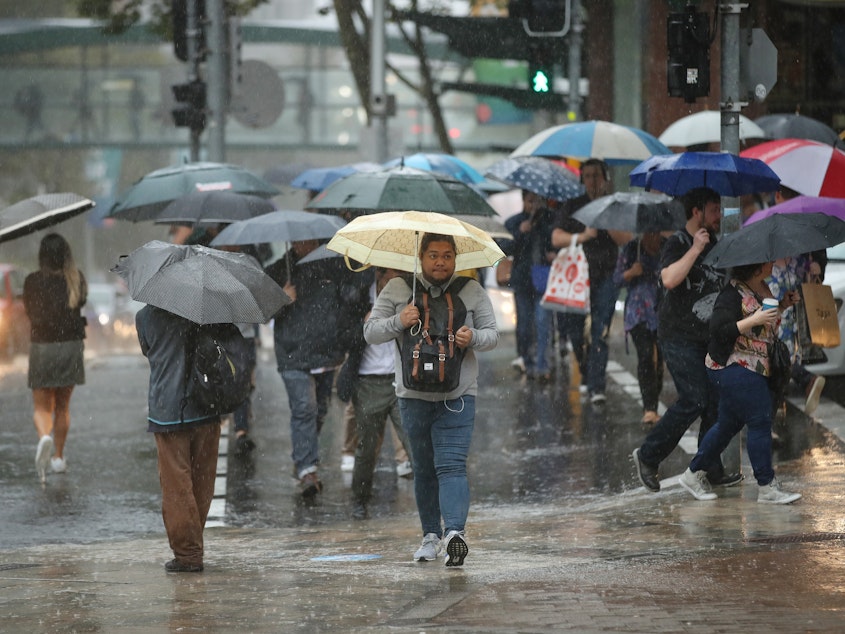 caption: People commute to work through heavy rain in Sydney on Friday. Severe weather brought warnings of floods and landslides for locations along much of New South Wales' coast, after months of concerns over wildfires.