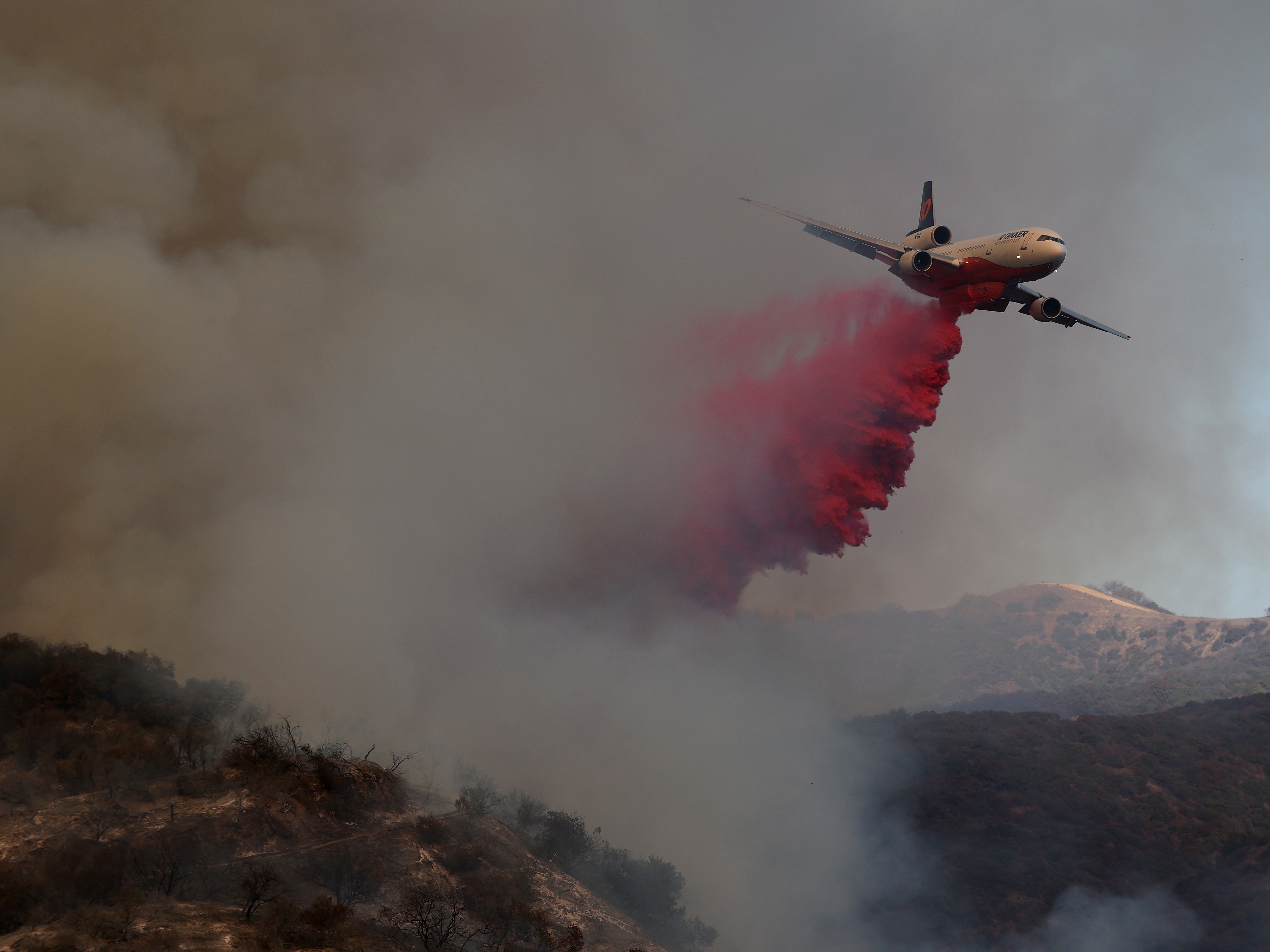 caption: A firefighting aircraft drops retardant ahead of the Palisades Fire on Jan. 11, 2025, in Los Angeles.