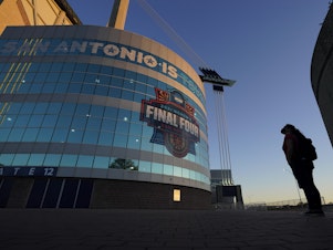 caption: A visitor looks up at the logo for the Women's Final Four in San Antonio, as the city prepares to host the Women's NCAA College Basketball Championship, in this March 18, 2021, file photo.