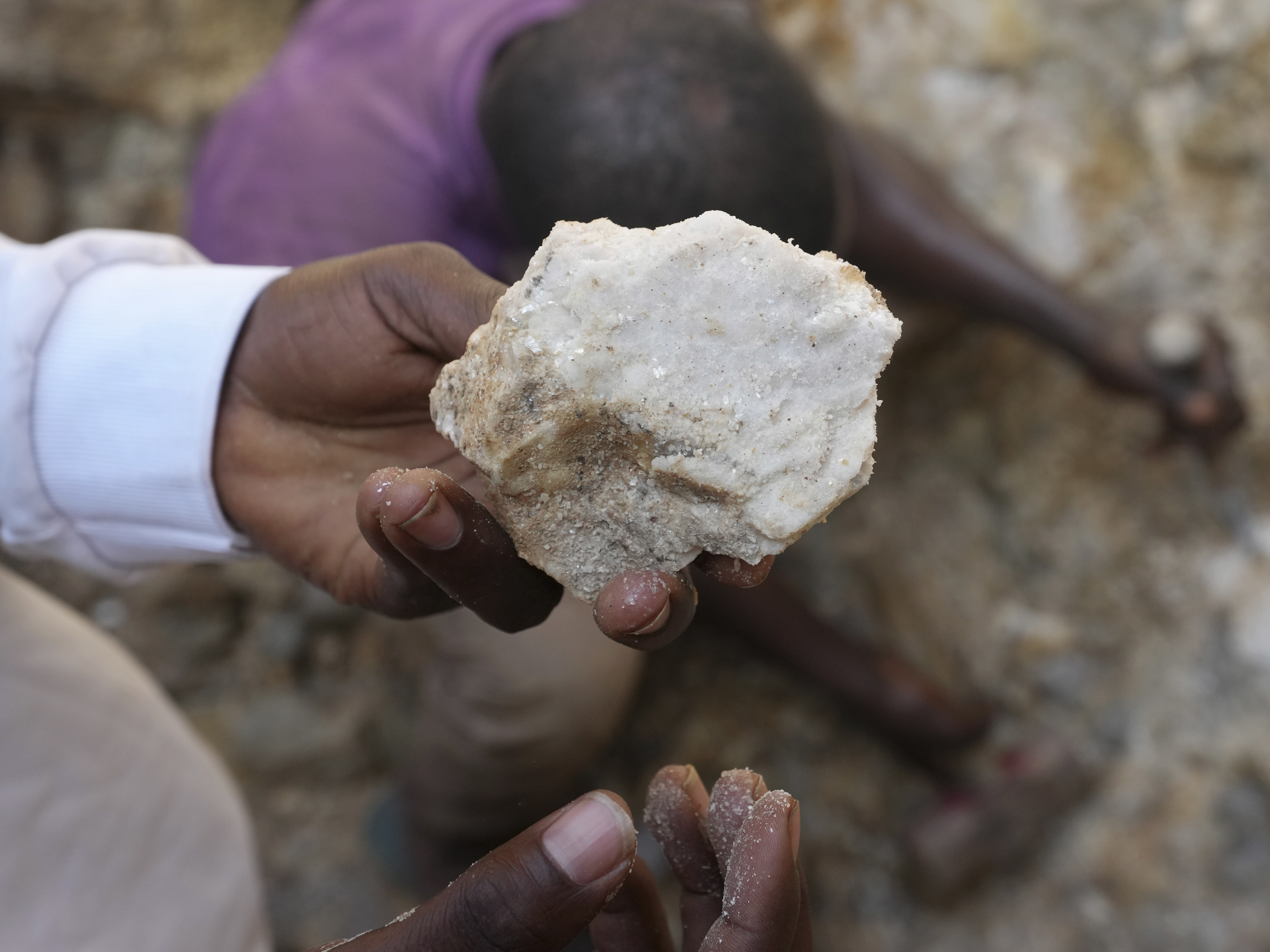 caption: A man shows lithium stone from an illegal mining site in Paseli, north central Nigeria, Tuesday, Nov 5, 2024.
