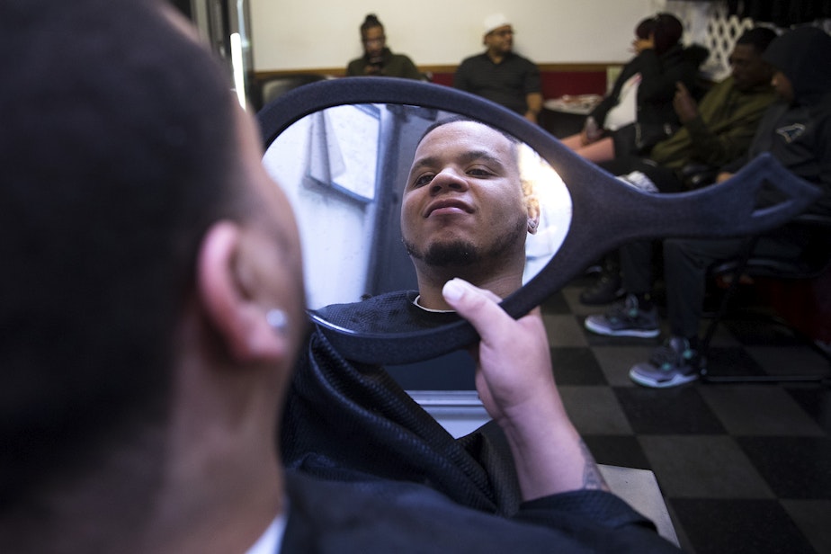caption: DaShawn Horne looks into a mirror after having his hair cut at Salon Edwards on Monday, December 31, 2018, in Federal Way.