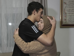 caption: Released Palestinian prisoner Muhammad Abu Al-Humus, 17, hugs his mother after arriving home in the east Jerusalem neighborhood of Issawiya, early Tuesday. Eleven Israelis were also released in the latest Israel-Hamas swap of captives.